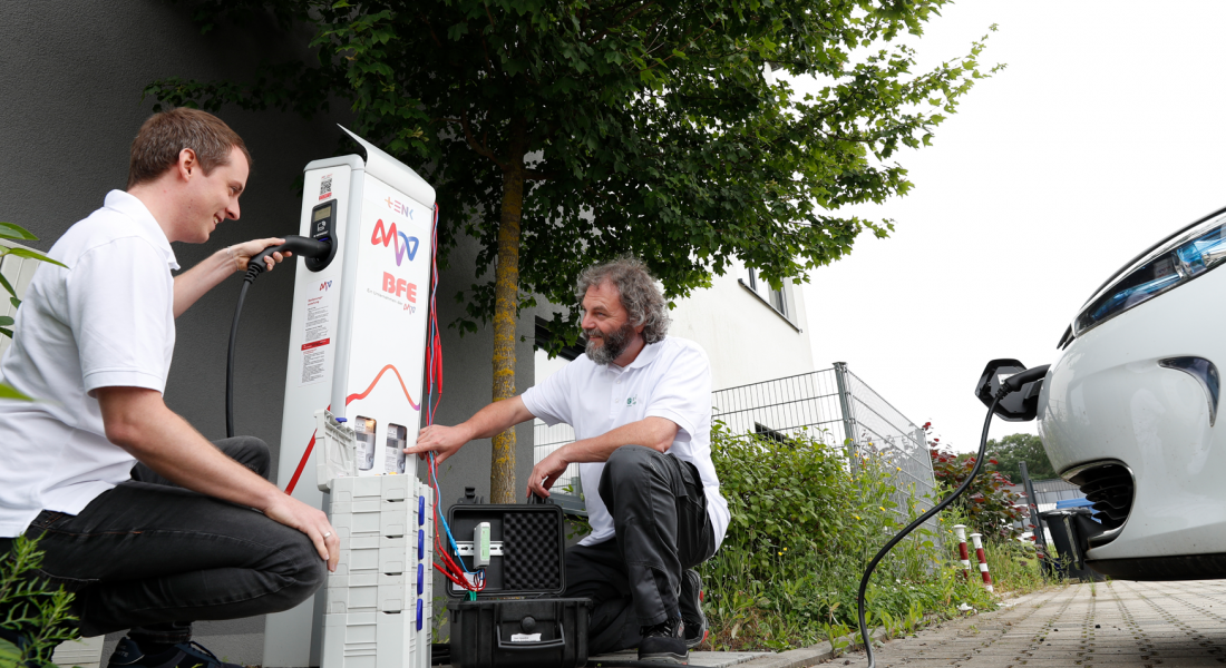 Zwei Techniker an der Ladesäule, Ladestecker im E-Auto