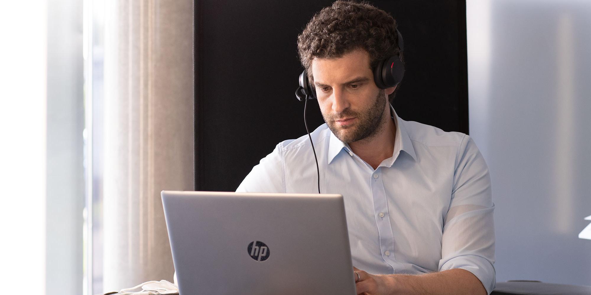 Junger Mann mit Headset vor Laptop