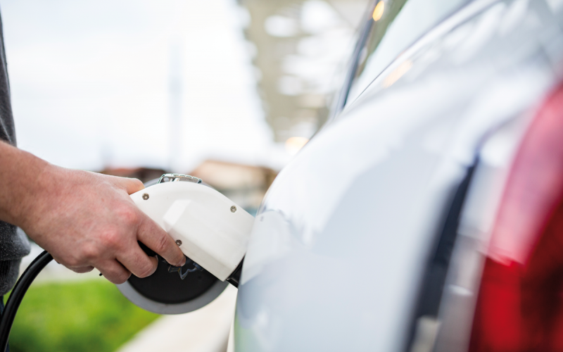 Eine Hand hält Tankstutzen im Elektroauto