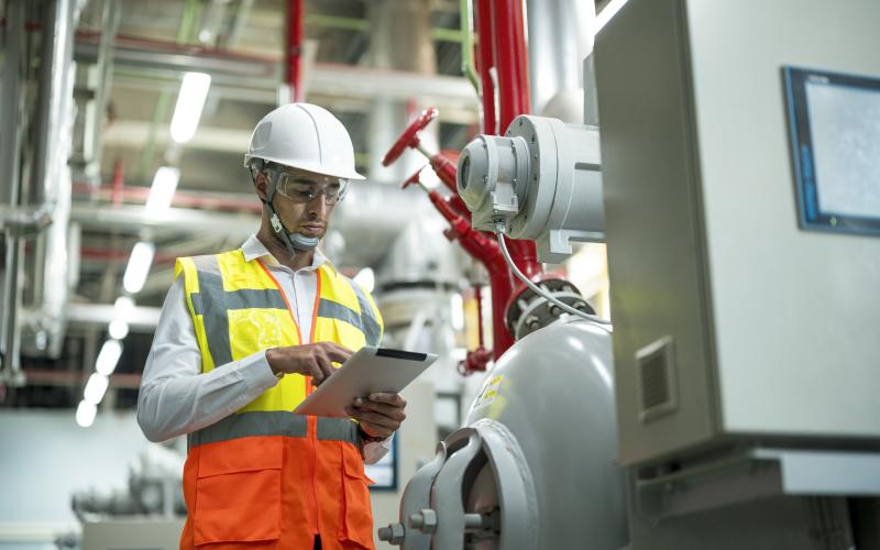 Mann an Ipad vor Heizungsanlage