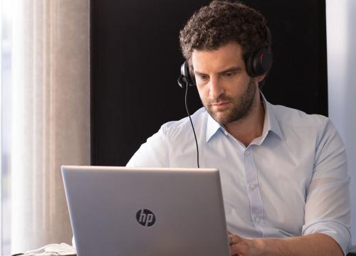 Junger Mann mit Headset vor Laptop