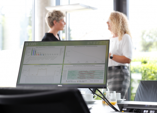 Softwarescreen, im Hintergrund zwei Frauen im Gespräch